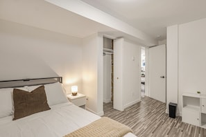 Une chambre à coucher avec un lit, une table de chevet, une lampe et une armoire.