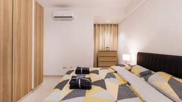 Una habitación de hotel con una cama, una mesita de noche, una lámpara, un armario y un equipo de aire acondicionado.