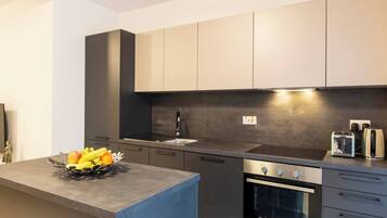 Una cucina moderna con forno integrato, lavello e una ciotola di frutta sul piano di lavoro.