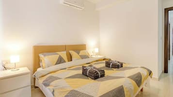Una camera d'albergo con un letto, comodini, una lampada e un condizionatore d'aria.