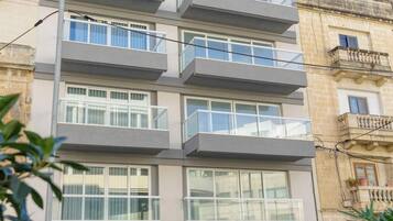 Un edificio residenziale a più piani con balconi, un basculante per garage e una cassetta delle lettere rossa.