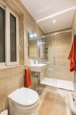 Ein modernes Badezimmer mit Toilette, Waschbecken und einer Dusche mit Glaswand.