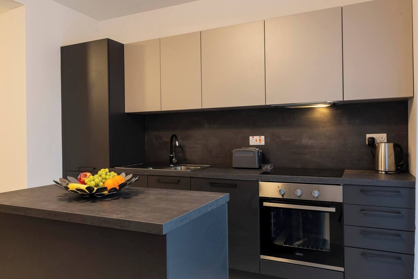 Una cucina moderna con forno integrato, un tostapane e un bollitore sul piano di lavoro.