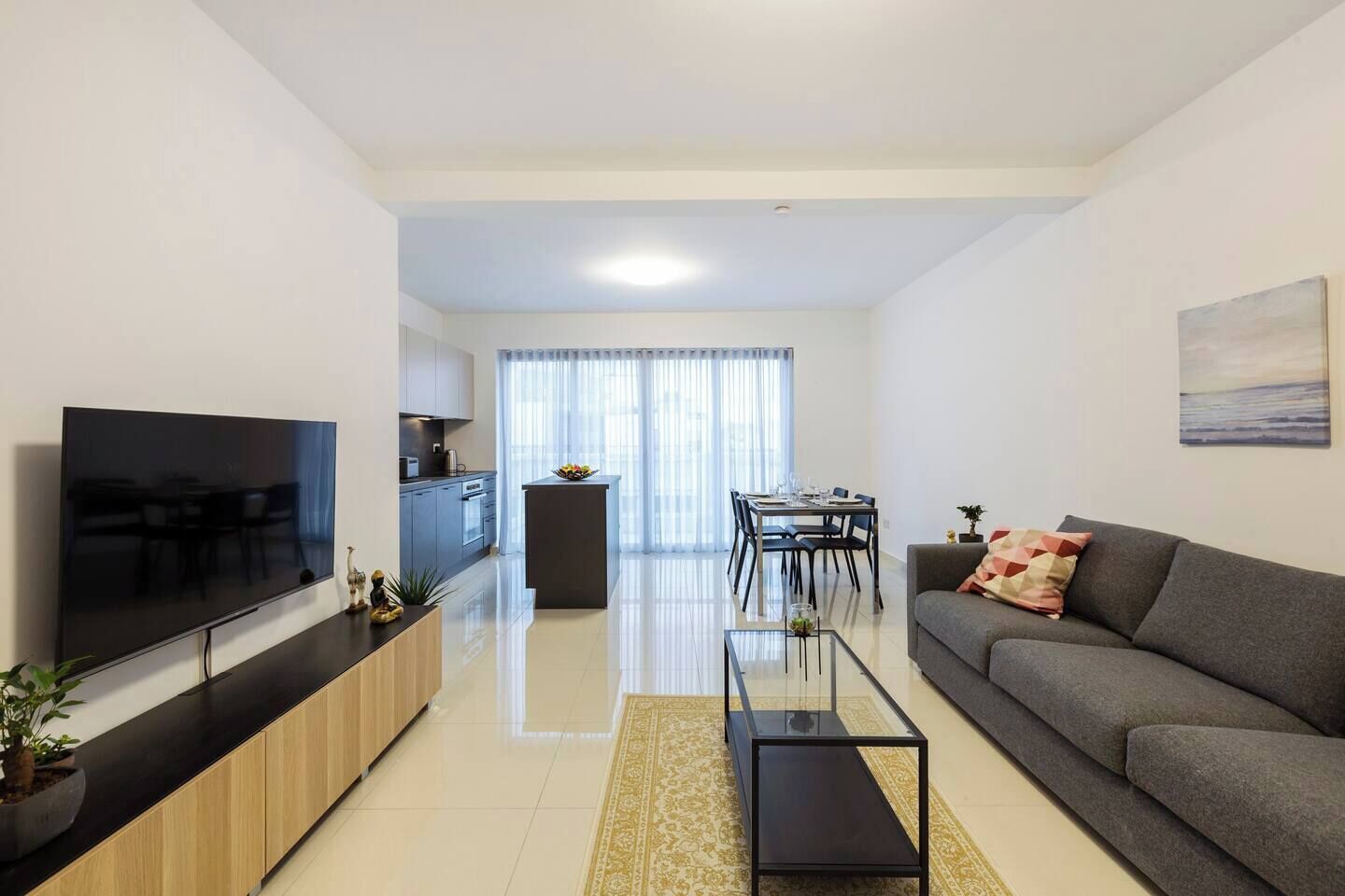 Un soggiorno moderno con una TV a schermo piatto, un divano, un tavolino da caffè e un'area pranzo con tavolo e sedie.