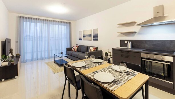 Un appartement moderne comprenant un coin repas, une kitchenette et un espace de vie avec un canapé et des rideaux.
