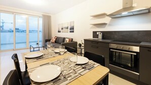 Un appartement moderne comprenant un coin repas, une cuisine et un balcon avec vue sur la ville.