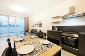 Eine moderne Wohnung mit Essbereich, Küche und einem Balkon mit Blick auf die Stadt.