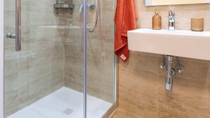 Une salle de bain moderne avec une douche à parois de verre, un lavabo blanc et un miroir au-dessus.