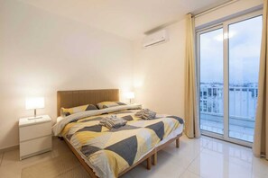 Ein Hotelzimmer mit einem Bett, Nachttischen, einem Fenster mit Blick und einer Klimaanlage.