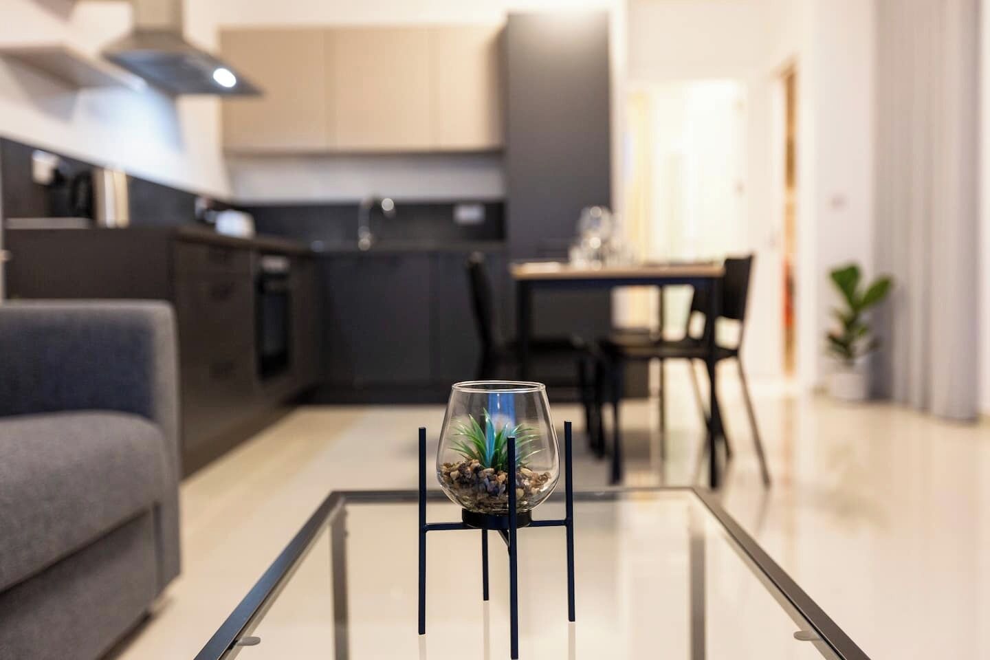 Un soggiorno moderno con un tavolino in vetro, un divano e, sullo sfondo, un'area da pranzo.
