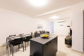 Ein modernes Wohnzimmer mit Essbereich, einem grauen Sofa und einem Flachbildfernseher.