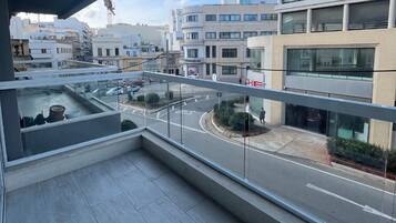 A balcony with a view of a city street, modern buildings, and a clear sky.