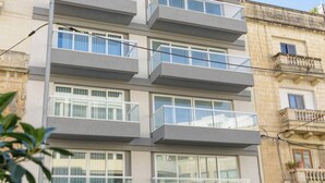 Un immeuble résidentiel à plusieurs étages, doté de balcons, de grandes fenêtres et d’une porte de garage.