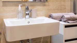 Une salle de bain avec un lavabo blanc, un miroir, une serviette et un flacon de savon pour les mains.