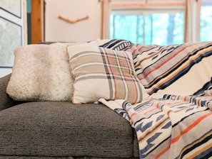 A couch with a plaid blanket and two pillows. - Harry's Hideaway | Hot Tub | Fire pit | Mt Rainier (Packwood)