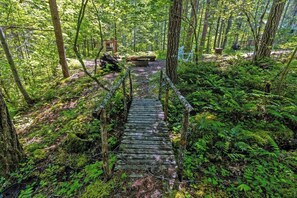 A wooden bridge in a forested area with dense foliage and a bench in the background. - Harry's Hideaway | Hot Tub | Fire pit | Mt Rainier (Packwood)