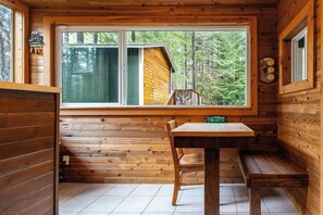 A wooden cabin interior with a window, a table, and a bench. - Harry's Hideaway | Hot Tub | Fire pit | Mt Rainier (Packwood)