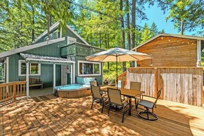 A wooden deck with a hot tub, outdoor seating, and a wooden structure. - Harry's Hideaway | Hot Tub | Fire pit | Mt Rainier (Packwood)