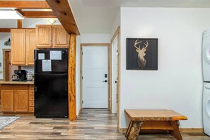 A compact kitchen with wooden cabinets, a black refrigerator, and a wooden bench. - Harry's Hideaway | Hot Tub | Fire pit | Mt Rainier (Packwood)