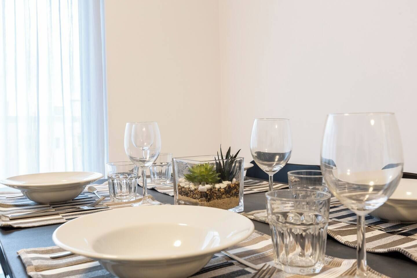 A dining table set with plates, glasses, and a decorative centerpiece.