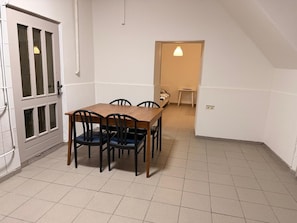 Un comedor con una mesa y sillas de madera, una puerta con paneles de vidrio y una lámpara sobre la mesa.