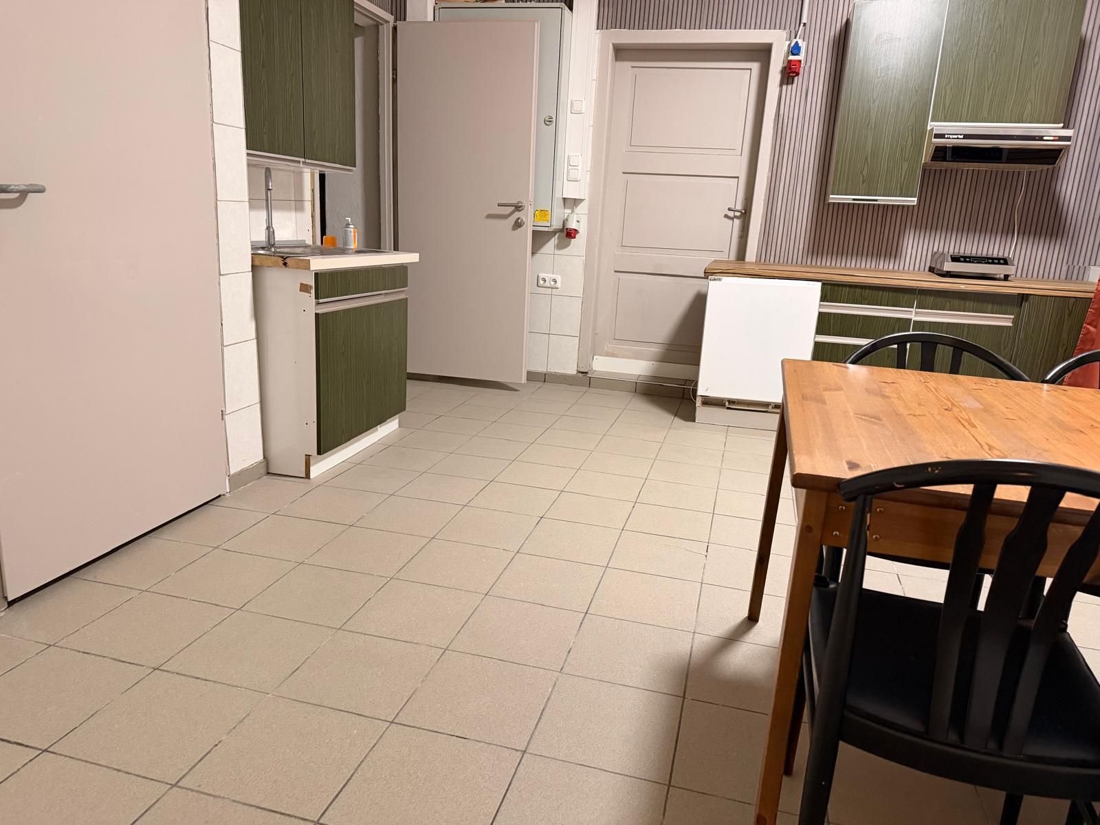 Una cocina compacta con una mesa de comedor y sillas, un refrigerador, una estufa y un microondas.