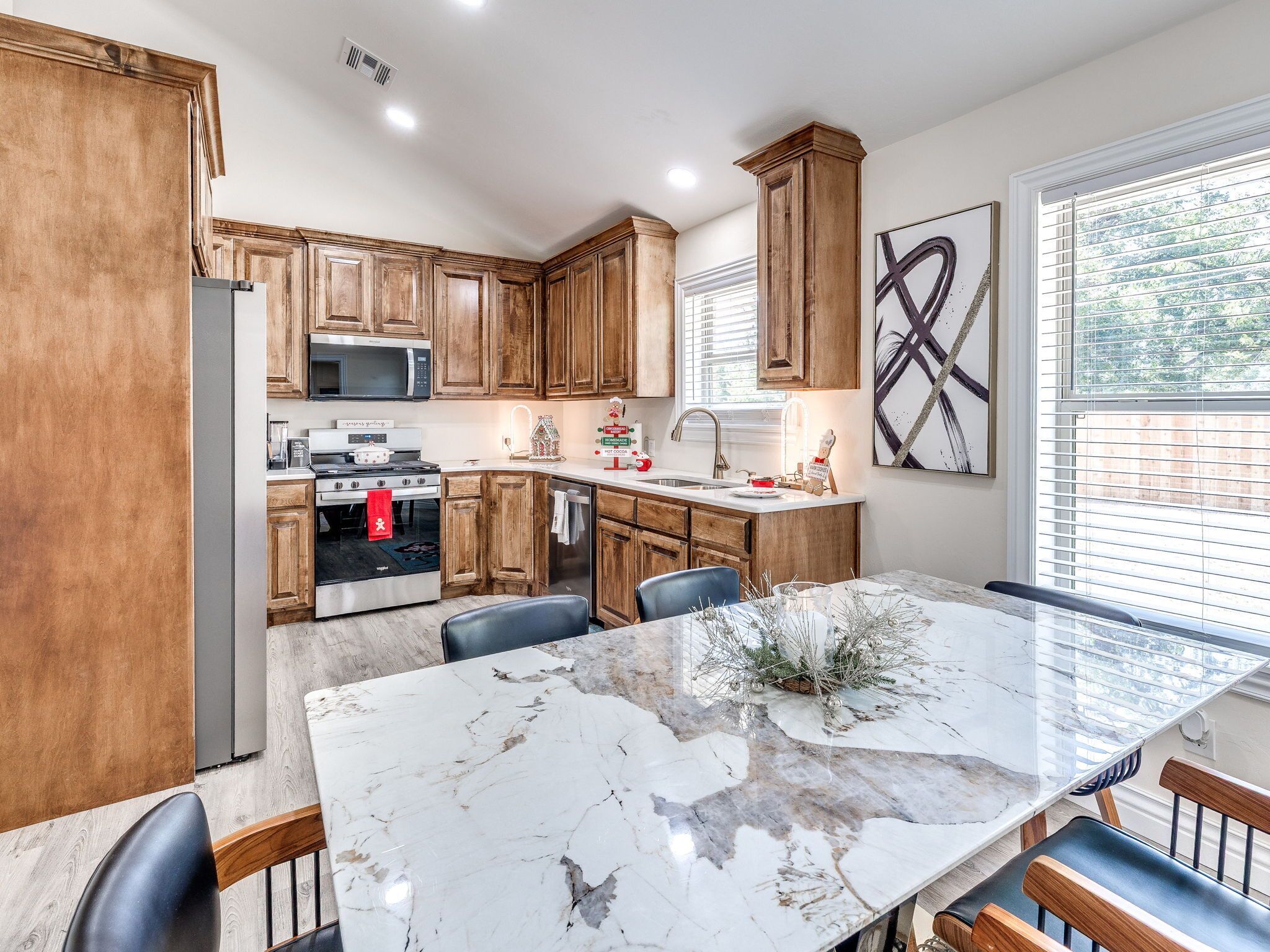 A modern kitchen with wooden cabinets, a stainless steel refrigerator, a microwave, and a stove.