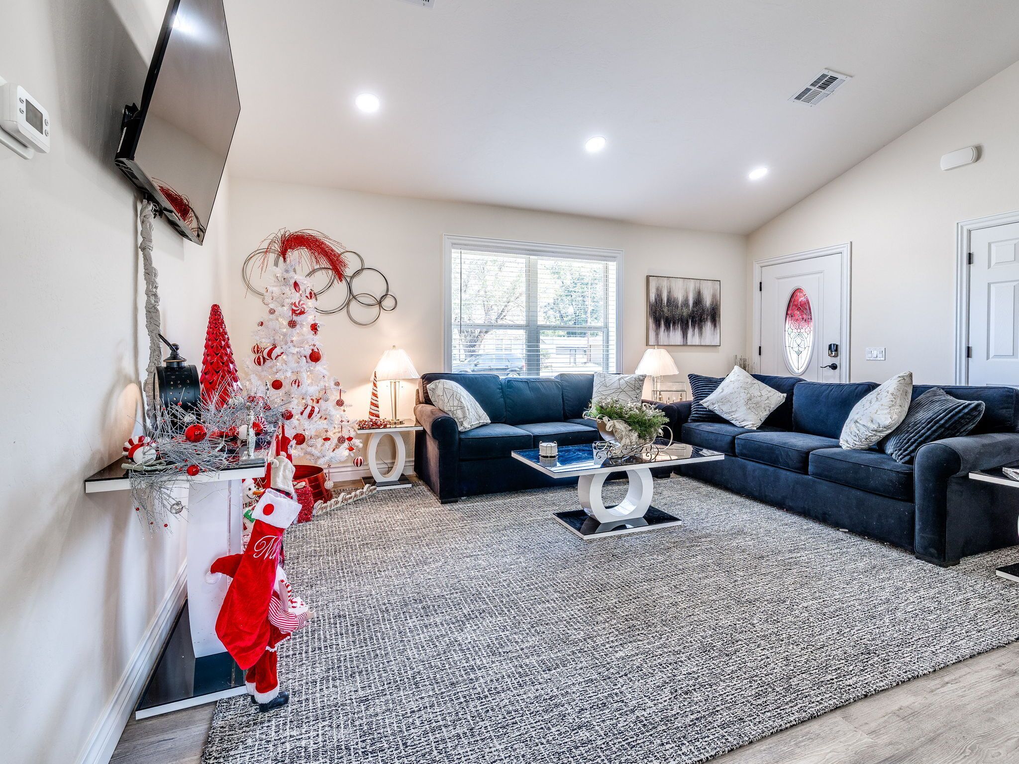 A modern living room with a blue sofa set, a coffee table, a fireplace, and holiday decorations.