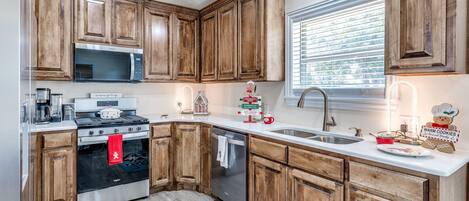 A kitchen with wooden cabinets, a stainless steel stove, a microwave, and a dishwasher.