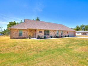 A two-story brick building with a flat roof, a front porch, and a small front yard. - Chickasha ChristmasTown - Family Holiday Retreat (Chickasha)