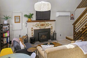 A living room with a fireplace, a television, and a staircase.