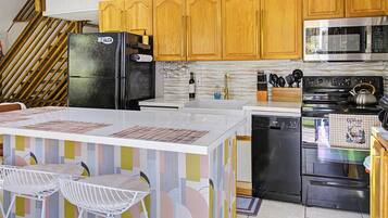 A kitchen with wooden cabinets, a black refrigerator, a microwave, a stove, and a dishwasher.