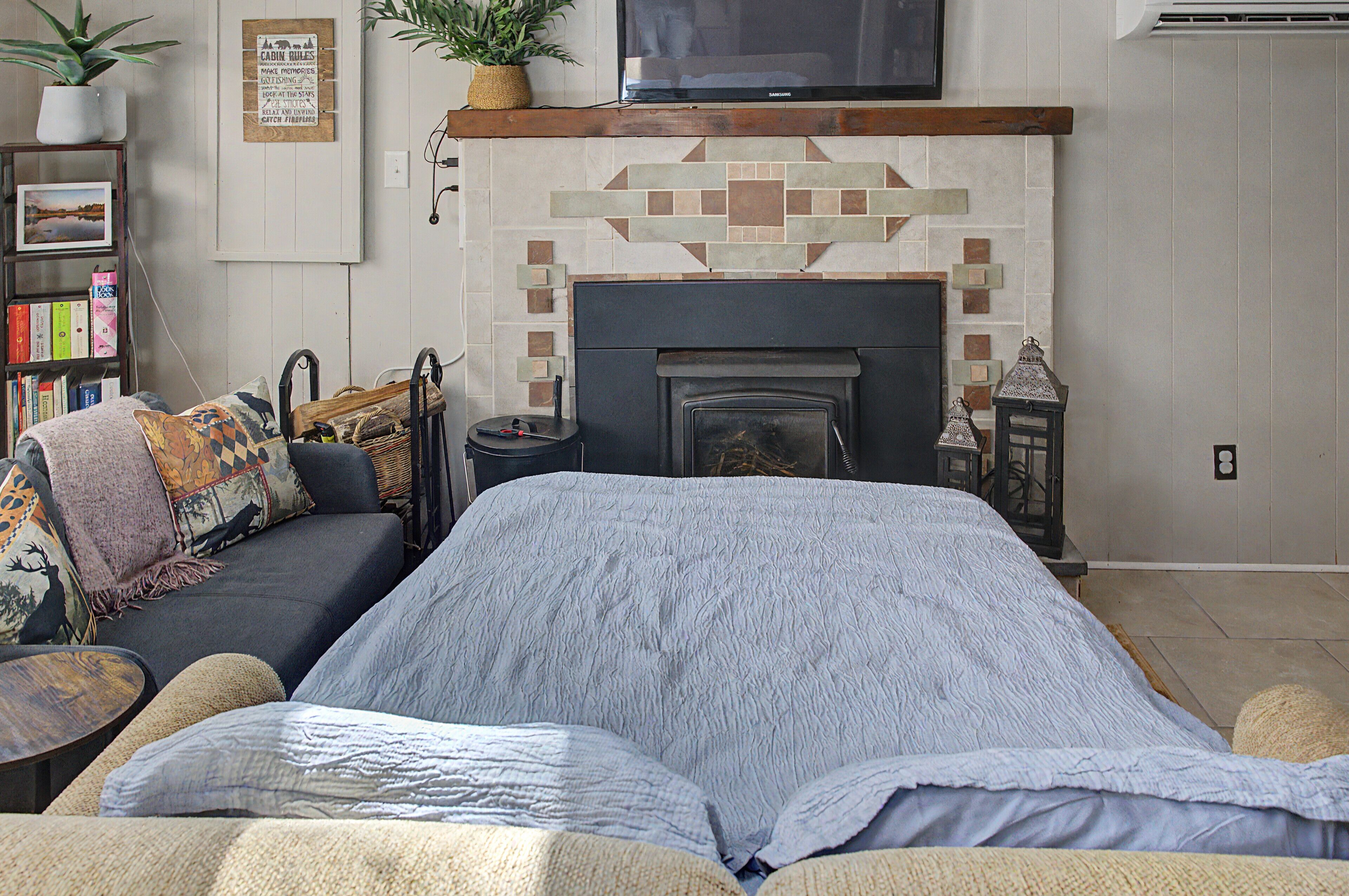 A cozy living room with a fireplace, a sofa, a television, and a bookshelf.