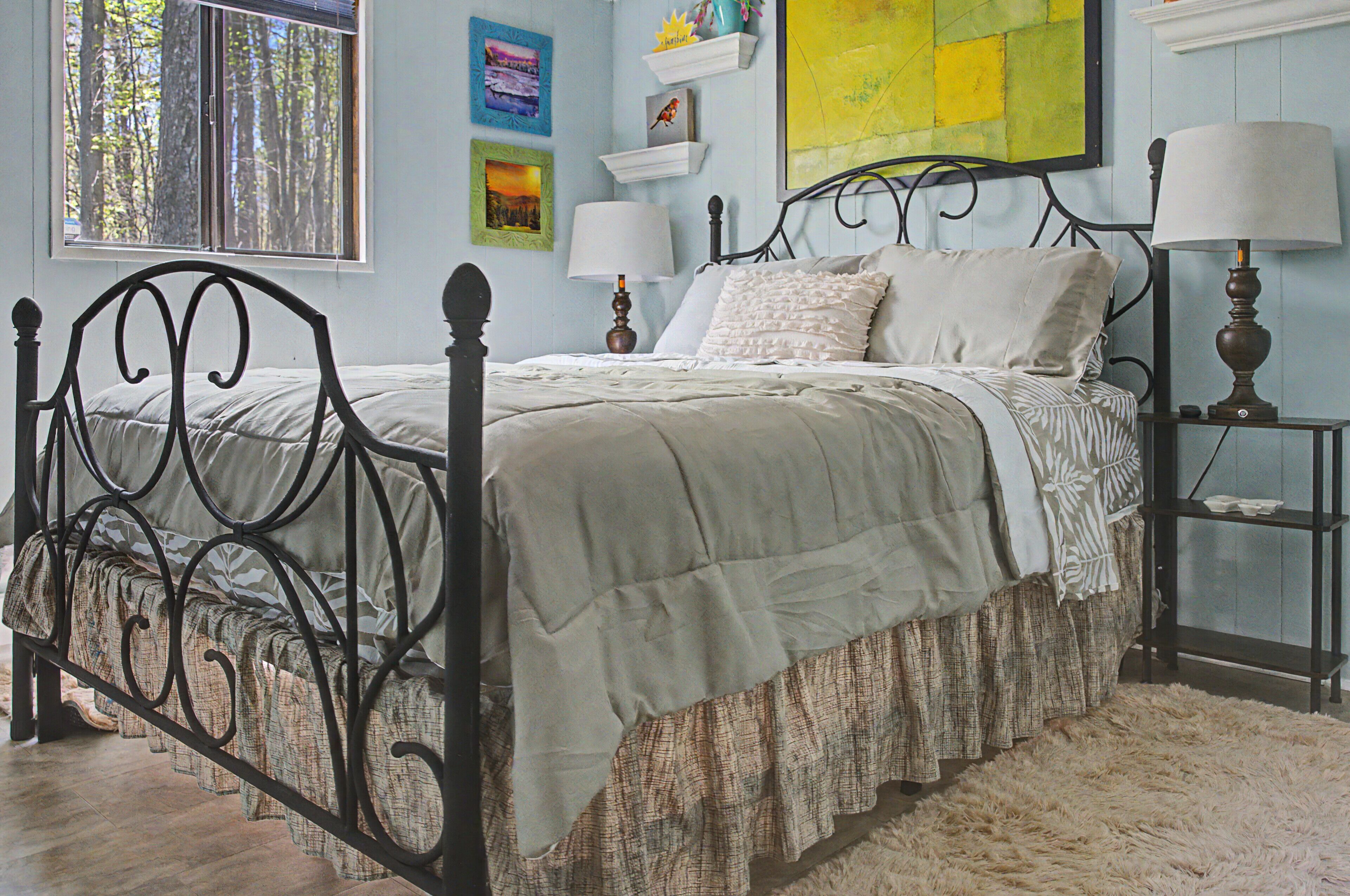 A bed with a headboard, bedside tables with lamps, and wall art.