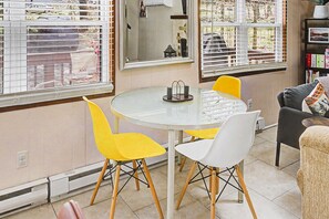 A dining area with a round table, two yellow chairs, and a white chair. - Serenity Chalet in Arrowhead Lake (Pocono Lake)