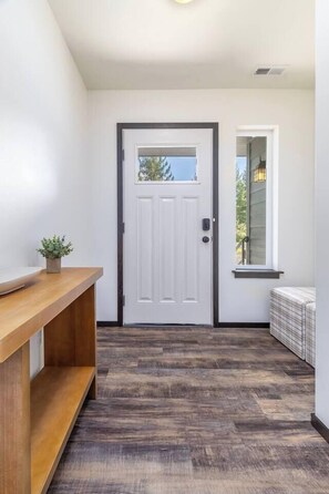 A hallway with a white door, a wooden bench, and a window with a view. - Jack’s Den | Sauna+Cold Plunge+A/C | Mt Rainier (Packwood)