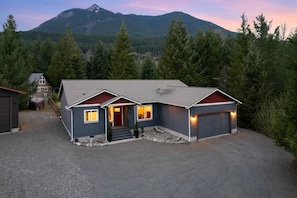 A two-story house with a garage, a covered driveway, and a mountain in the background. - Jack’s Den | Sauna+Cold Plunge+A/C | Mt Rainier (Packwood)