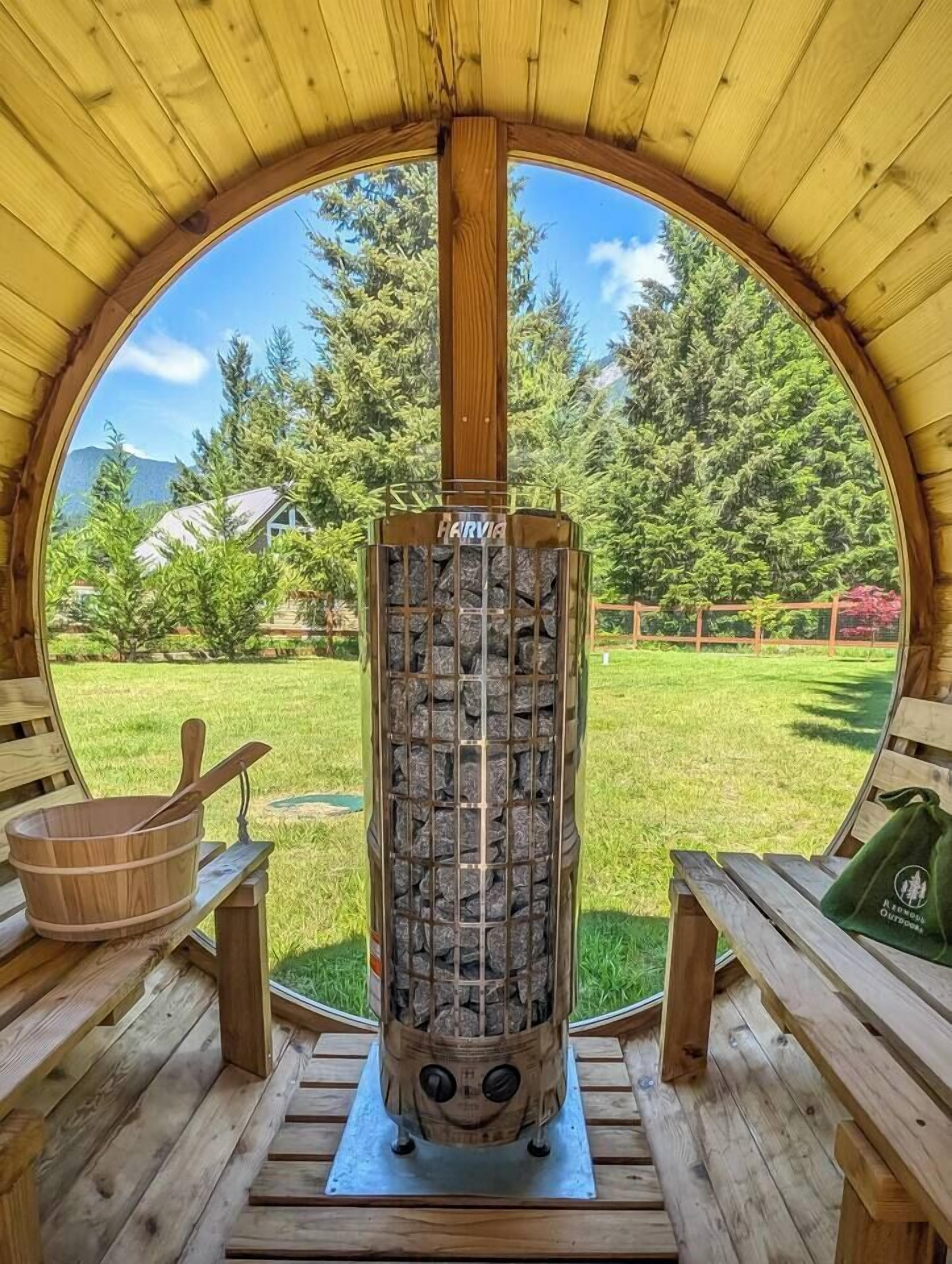 A circular wooden structure with a stone fireplace, wooden benches, and a view of a green landscape.
