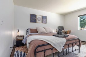 Ein Schlafzimmer mit einem Bett, Nachttisch, Lampe und einem Kunstwerk an der Wand.