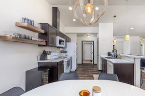 A modern kitchen with a central island, built-in appliances, and a dining area with a white table. - Jack’s Den | Sauna+Cold Plunge+A/C | Mt Rainier (Packwood)