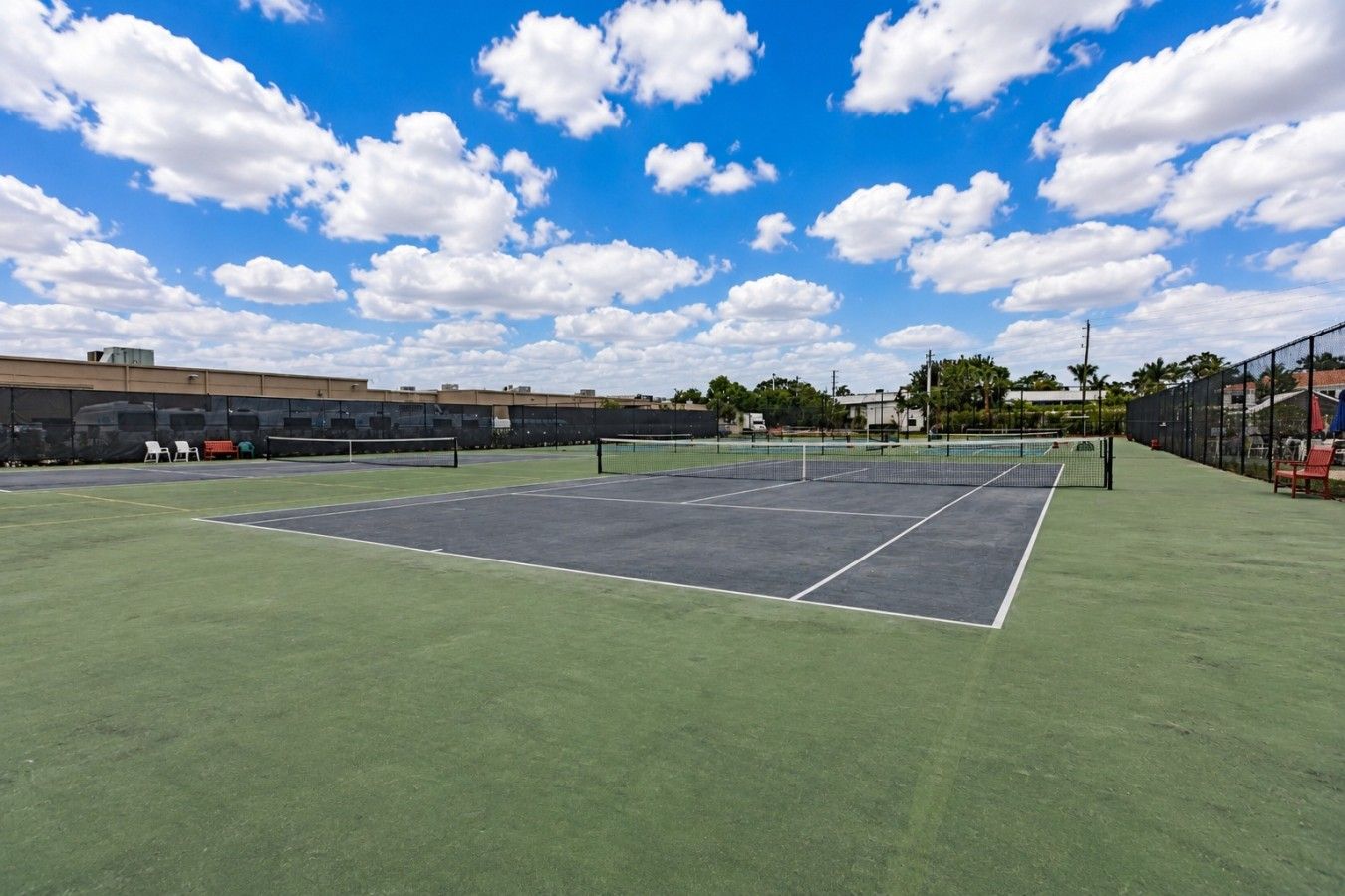 Ein Tennisplatz im Freien mit Netz, grünem Rasen und blauem Himmel.