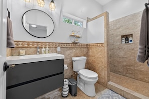 Une salle de bain comprenant des toilettes, un lavabo et un espace douche.