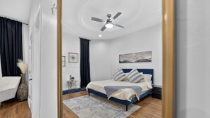 Ein Schlafzimmer mit Bett, Deckenventilator, Teppich und Nachttisch.