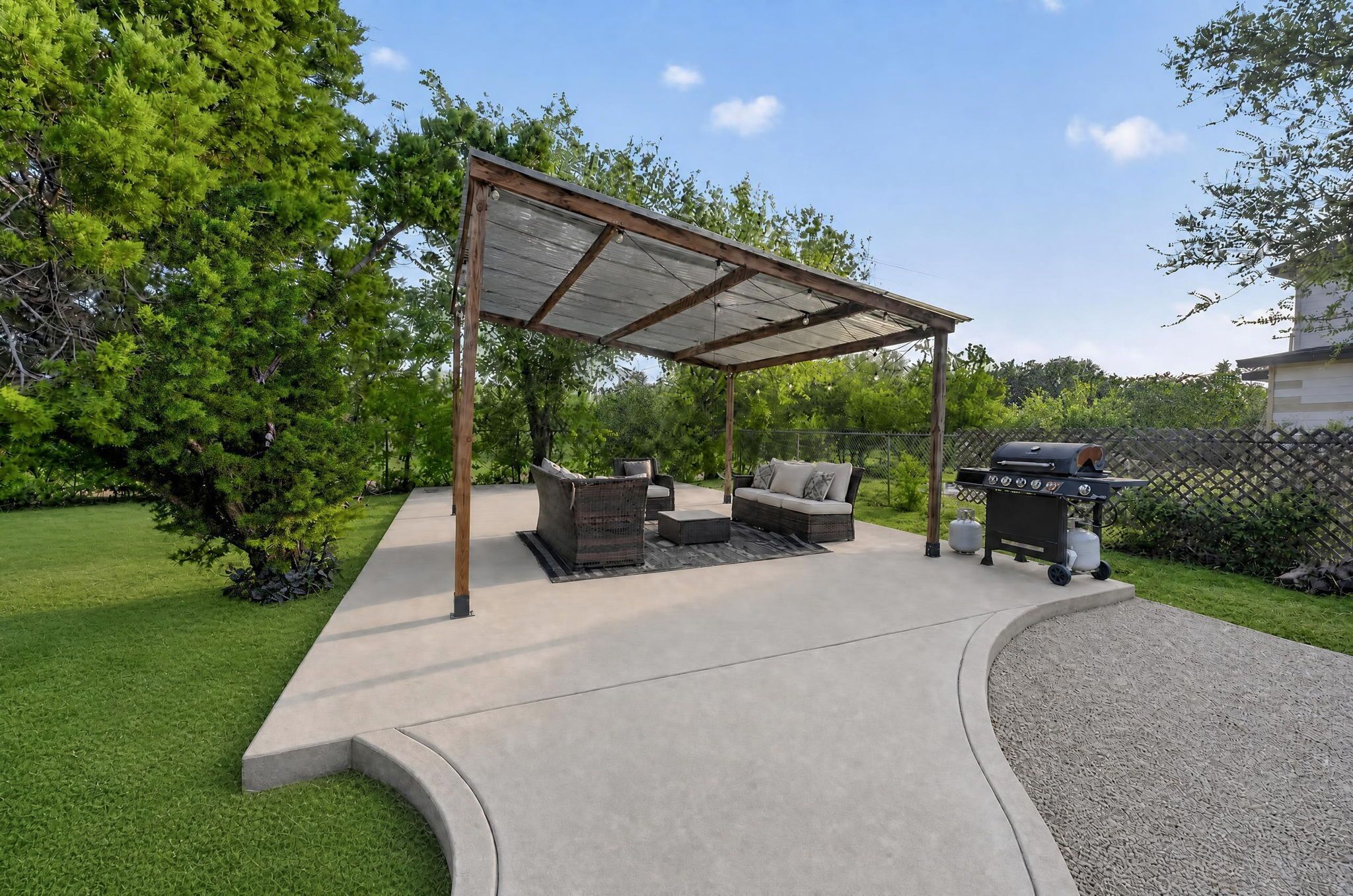 A covered patio area with outdoor furniture and a barbecue grill.