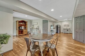 A spacious dining area with a round table and chairs, a wooden cabinet, and a refrigerator in the background. - Spacious 5-bedroom house in peaceful Monument perfect for families (Monument)