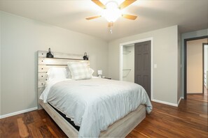 A bedroom with a bed, a ceiling fan, a nightstand, and a door. - Spacious 5-bedroom house in peaceful Monument perfect for families (Monument)