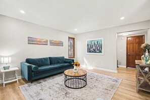 A living room with a blue sofa, a round coffee table with a vase, and artwork on the walls. - Spacious 5-bedroom house in peaceful Monument perfect for families (Monument)