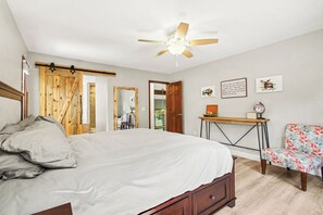A bedroom with a bed, a desk, a chair, a ceiling fan, and a door leading to another room. - Spacious 5-bedroom house in peaceful Monument perfect for families (Monument)