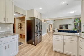 A modern kitchen with white cabinetry, a stainless steel refrigerator, and a wooden floor. - Spacious 5-bedroom house in peaceful Monument perfect for families (Monument)