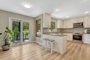 A modern kitchen with a central island, white cabinetry, and a view to an outdoor patio. - Spacious 5-bedroom house in peaceful Monument perfect for families (Monument)
